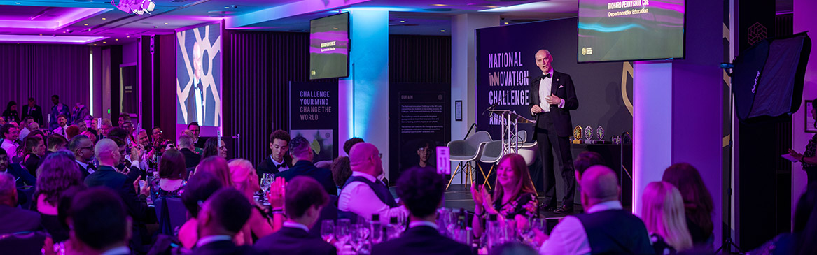 National Innovation Challenge Awards night with former Skills England Chair Richard Pennycook speaking on stage in front of the audience of guests and winners.