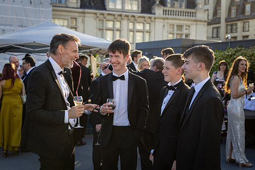 Gavin Hughes - Principal, Richmond Upon Thames College - speaking with some of the secondary school finalists for the National Innovation Challenge 2025, who are attending the awards evening. They are all dressed in tuxedos.