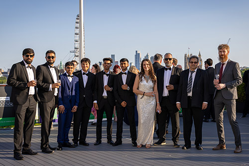 HRUC staff and students dressed in formal wear attending the National Innovation Challenge Awards night. They are outside on a balcony with the skyline of London behind them.