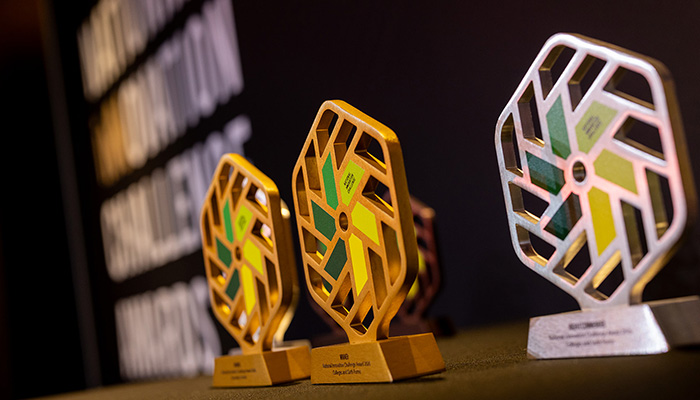 NIC silver and gold trophies sitting on a table with the logo/words in the background on a wall