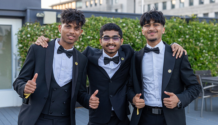 NIC 2026 colleges category winners - Shlok, Xainaldo and Faithon from Uxbridge College - dressed in tuxedos and giving the thumbs up on the rooftop terrace at the National Innovation Challenge Awards Ceremony.