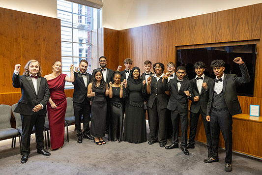 Yaseen Akhtar, Managing Director of the West London Institute of Technology, HRUC with the winners and finalists of the National Innovation Challenege at the awards ceremony reception. They are all dressed in formal wear and raising their arms.