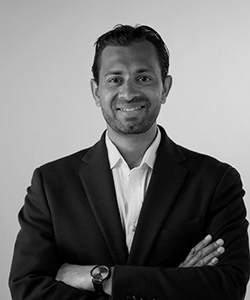 Sarwar Khan standing with his arms folded and smiling. 