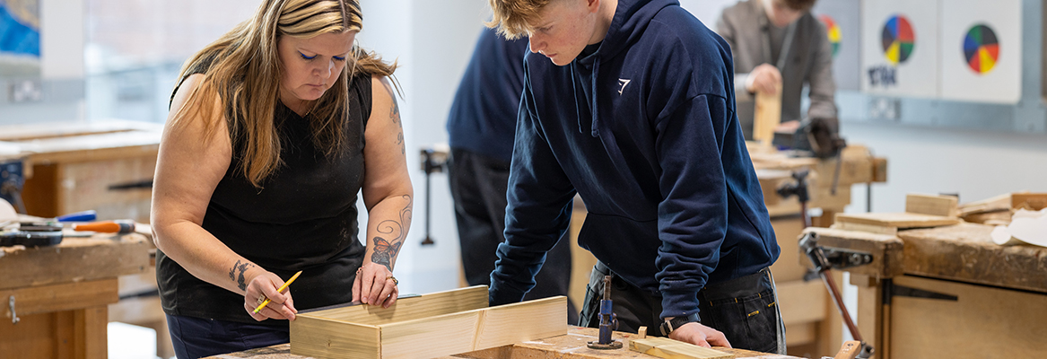 A Richmond College teacher demonstrating to a student carpentry and joinery skills