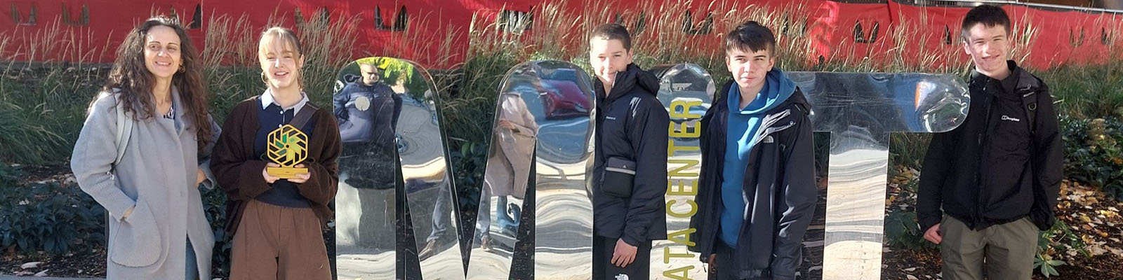 The National Innovation Challenge winners standing next to a mirrored MIT sign.