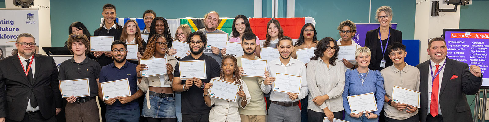 Harrow, Richmond and Uxbridge Colleges (HRUC) students who took part in the Turing Scheme Overseas Placements  in a group holding up their certificates and smiling. They are joined by Jo Withers, Liam Plumridge and Tim Wells.