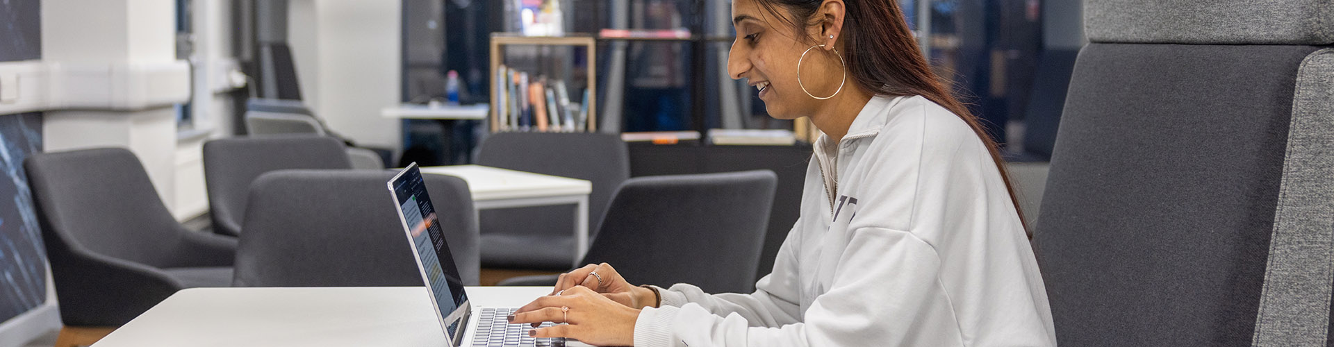 A female Uxbridge student working at her laptop.