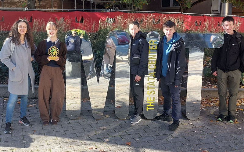 The National Innovation Challenge winners standing next to a mirrored MIT sign.