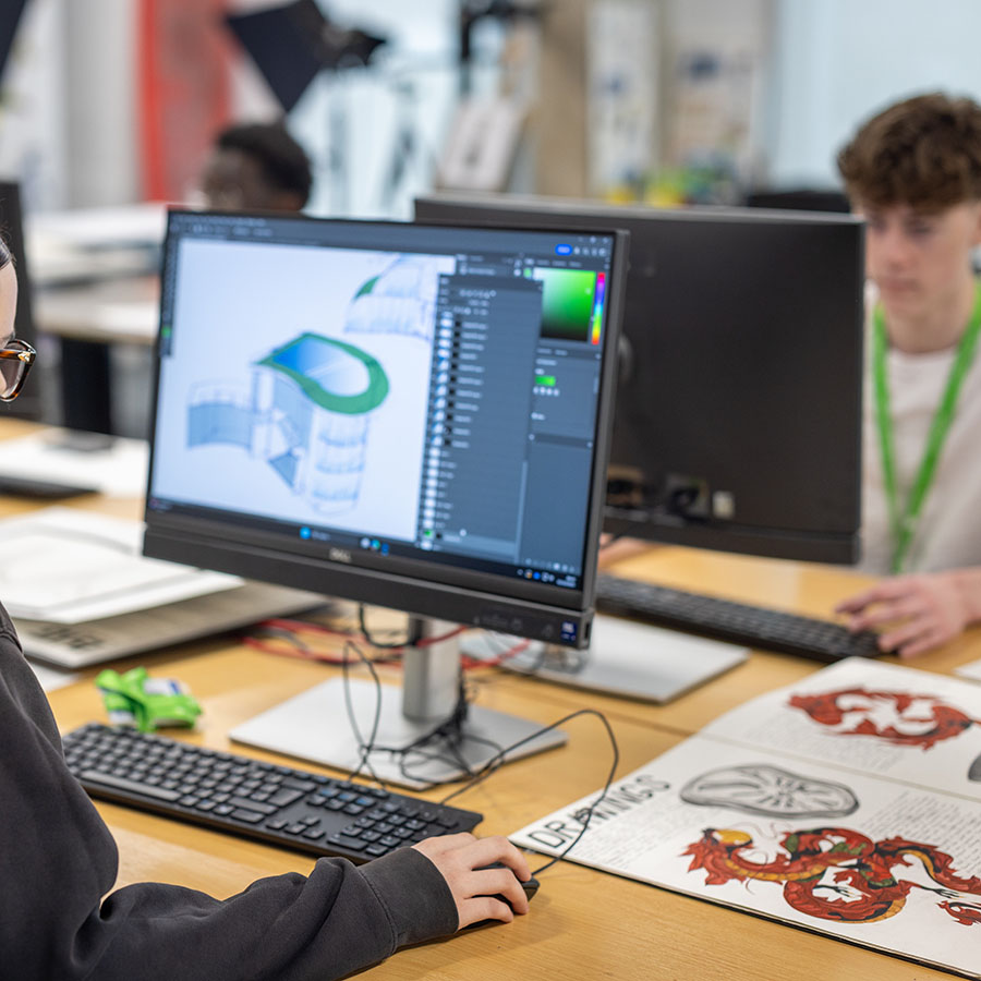 Richmond upon Thames College student at a computer doing course work. Her hand is on the mouse and they are wearing a black hoodie. 