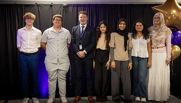 HRUC Skills Competition winners from Richmon Upon Thames College standing with Gavin Hughes, Principal on stage.