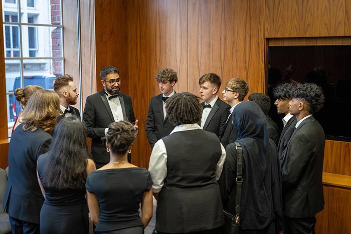 Yaseen Akhtar, Managing Director of the West London Institute of Technology, HRUC with the winners and finalists of the National Innovation Challenege at the awards ceremony reception. They are all dressed in formal wear and standing in a circle listening to him.