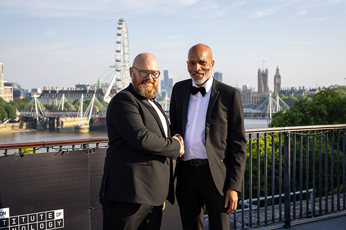 Ben Watson, Regional Data Centre Operations Leader for Amazon Web Services and Clive Hodge, Principal at HRUC - both dressed in tuxedos shaking hands on the terrace of the IET at the National Innovation Challenge Awards ceremony. 