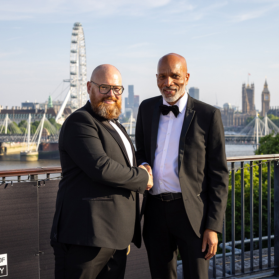 Ben Watson, Regional Data Centre Operations Leader for Amazon Web Services and Clive Hodge, Principal at HRUC - both dressed in tuxedos shaking hands on the terrace of the IET at the National Innovation Challenge Awards ceremony. 