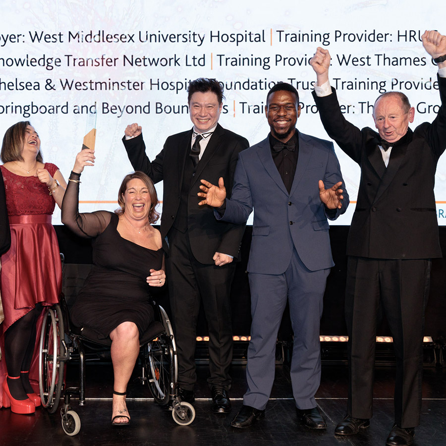 Apprentice of the Year Winner – Joanne McSweeney holding her award and cheering with others on stage at the 2026 West London Business Awards.