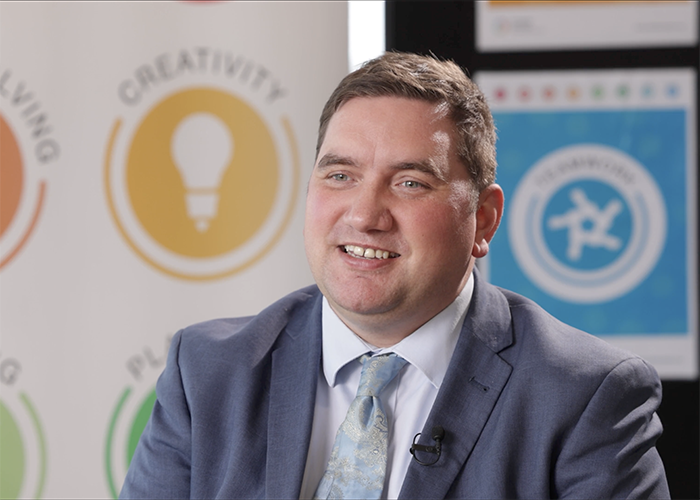 Liam Plumridge, HRUC’s Assistant Director for Enhanced Skills and Employability. He is wearing a grey suit, white shirt and light blue tie.