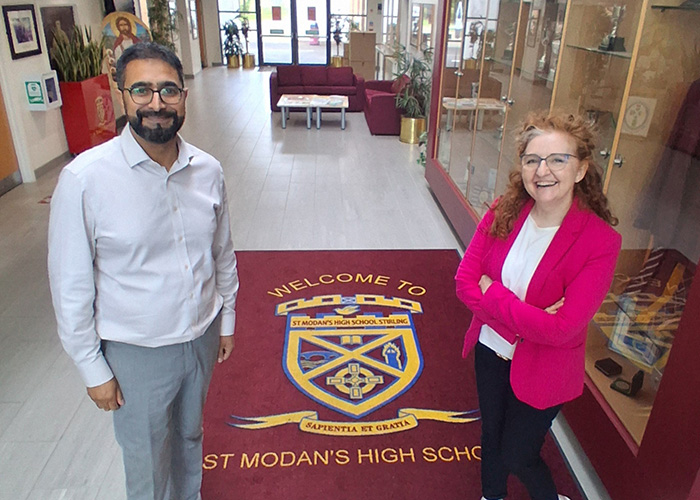 Yaseen Akhtar, Managing Director of the West London Institute of Technology, and Dr Niamh Shaw, NIC ambassador standing in the reception of St Modan's High School. There is a floor mat with the school emblem that they are standing on.