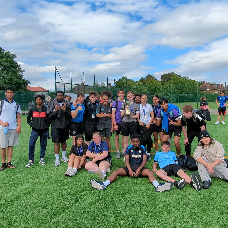 Our students gathered together on a sports field for the HRUC Sports Day - posing for a group photo. They are all dressed in sports gear and one female student is holding a cup in the middle of the group.