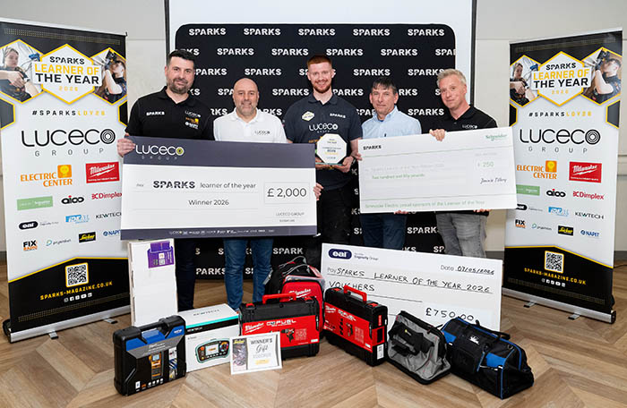Samuel Stevely - SPARKS Learner of the Year 2026 - holding his award and standing with others in front of Sparks banners and they are holding large winner cheques and his prize bundle is at his feet, including various tools in cases.