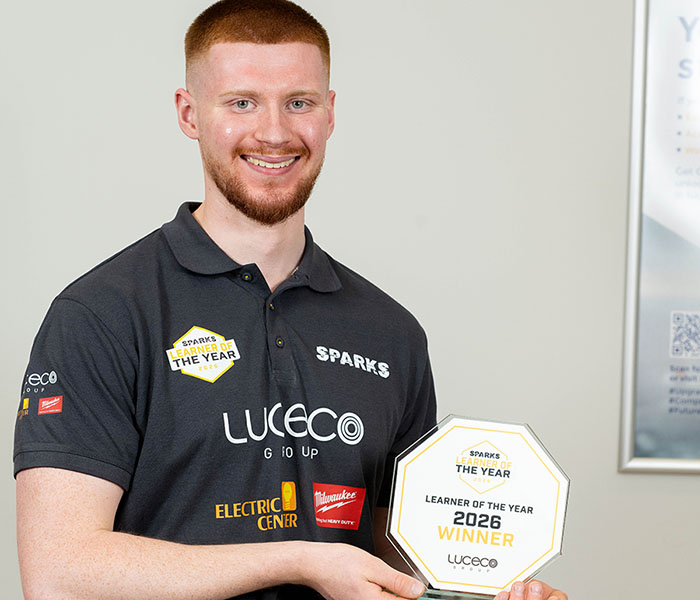 Samuel Stevely - SPARKS Learner of the Year 2026 - holding his award and wearing a black polo shirt with brands and logos on it.