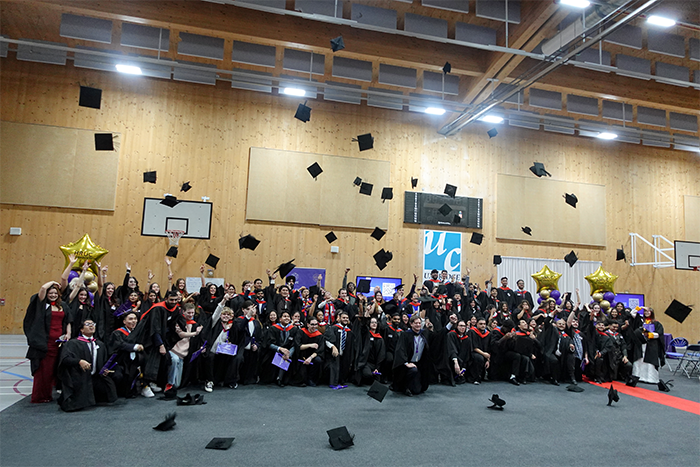 All the HRUC HE graduates throwing their caps in the air in a group photo. They are in the Uxbridge College Sports Hall.